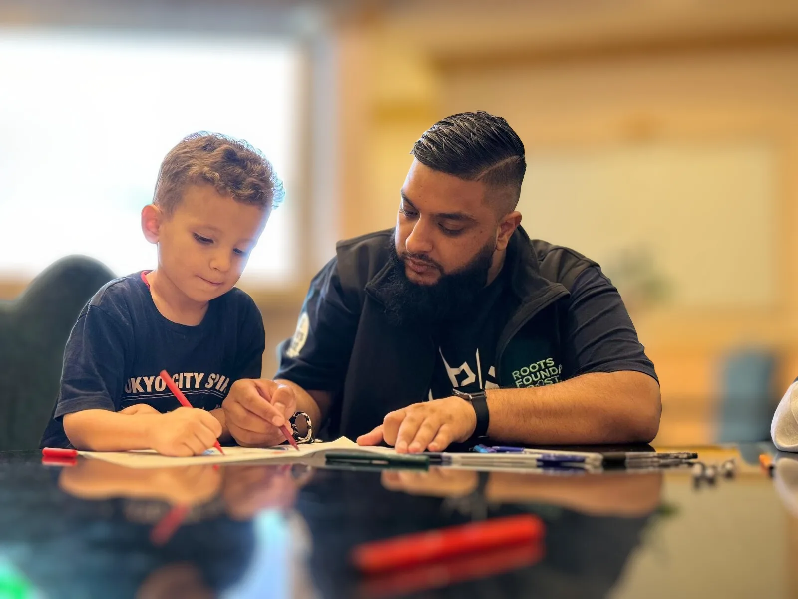 Roots Foundation Trust volunteer helping a young boy with his school work